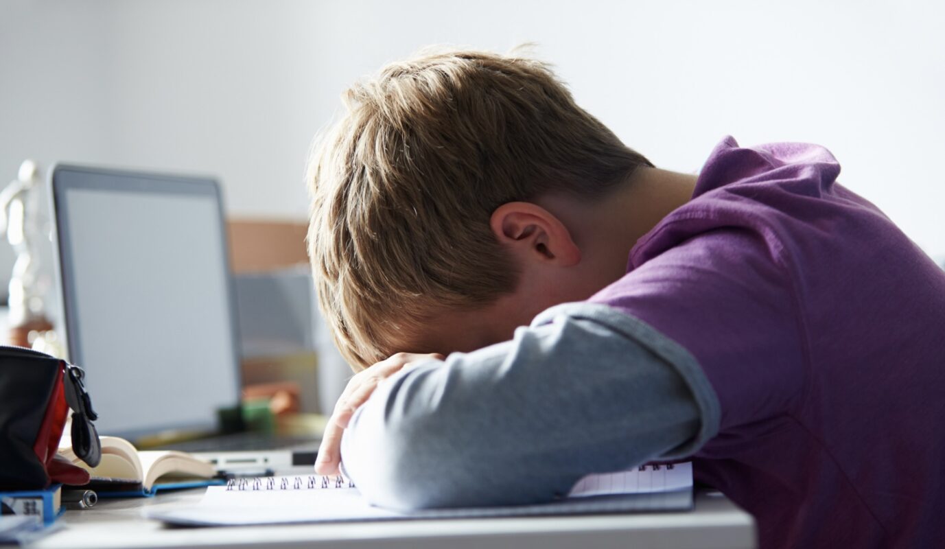 Jongen met hoofd op bureau