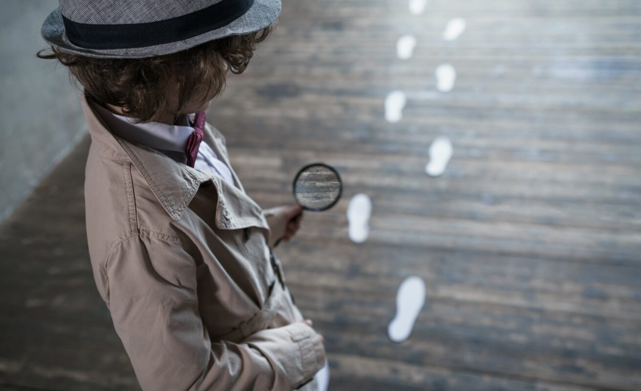 Kind met vergrootglas kijkt naar sporen van voetafdruk op de vloer