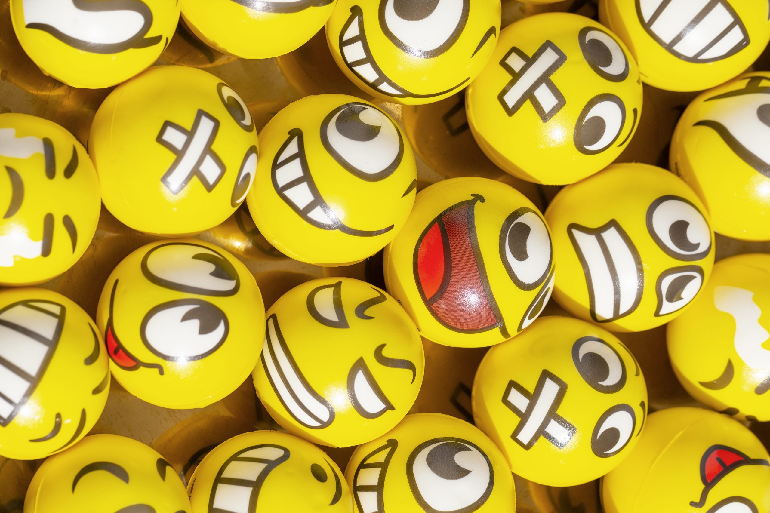 Verschillende gele ballen met emoji-gezichtjes die digitale communicatie van jongeren verbeelden