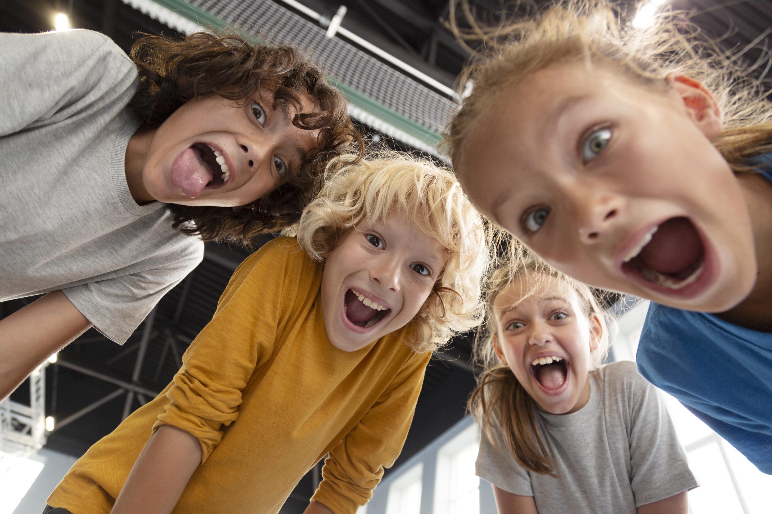 Vier kinderen lachen en roepen vrolijk in de camera tijdens een actieve groepsactiviteit