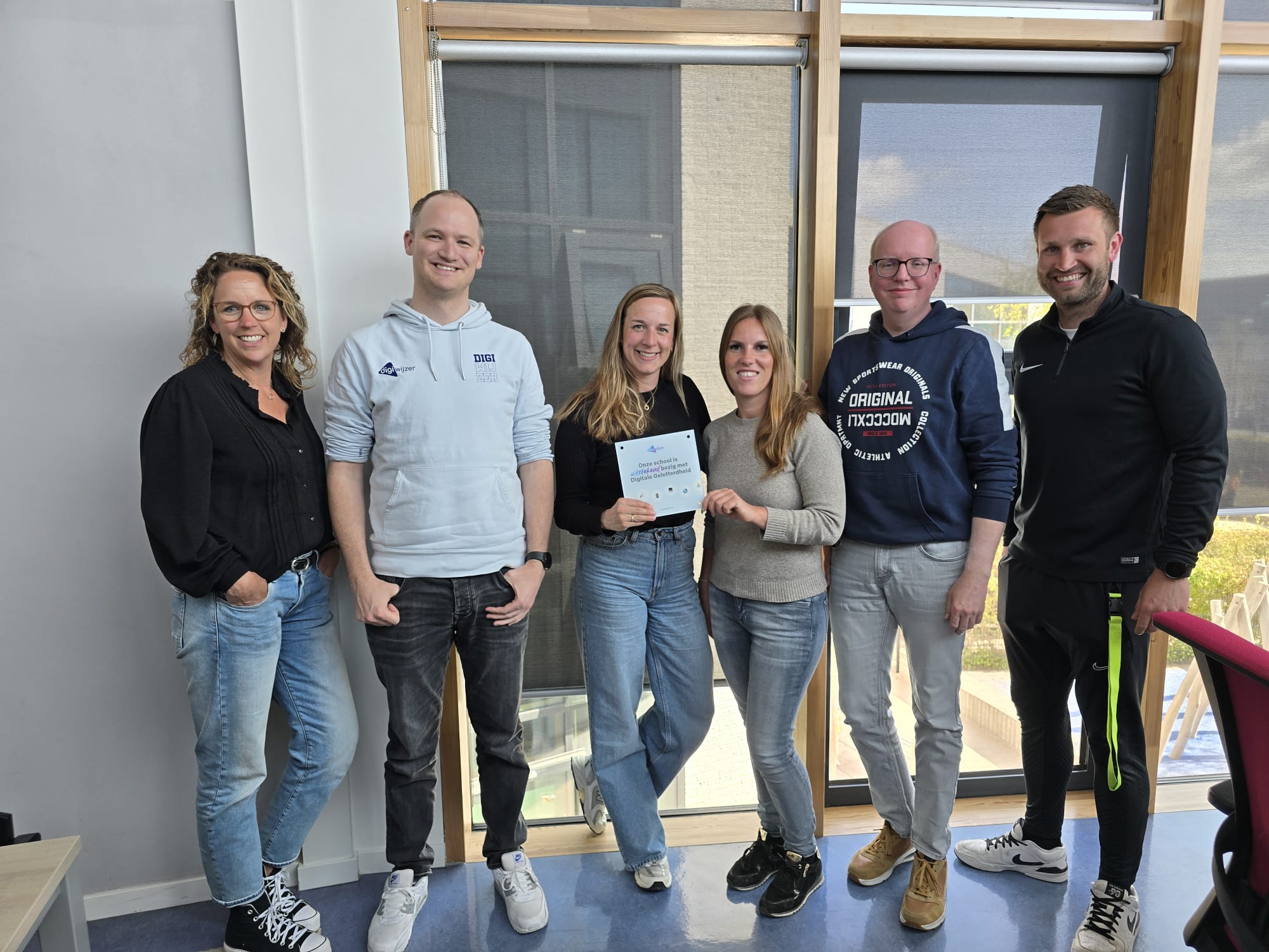 Team van IKC Da Vinci in Zoetermeer ontvangt erkenningsschildje voor digitale geletterdheid van Digiwijzer.