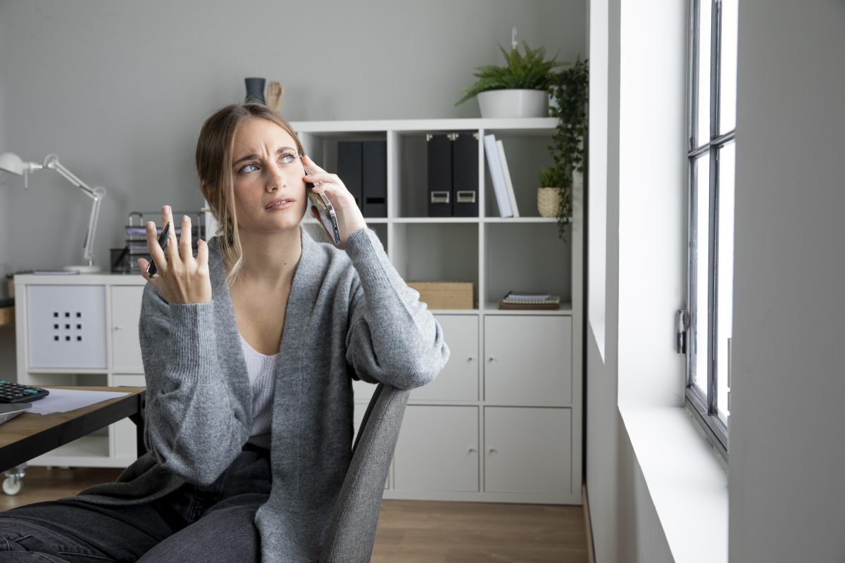 Vrouw kijkt wantrouwend tijdens telefoongesprek, mogelijk slachtoffer van AI-telefoonfraude.