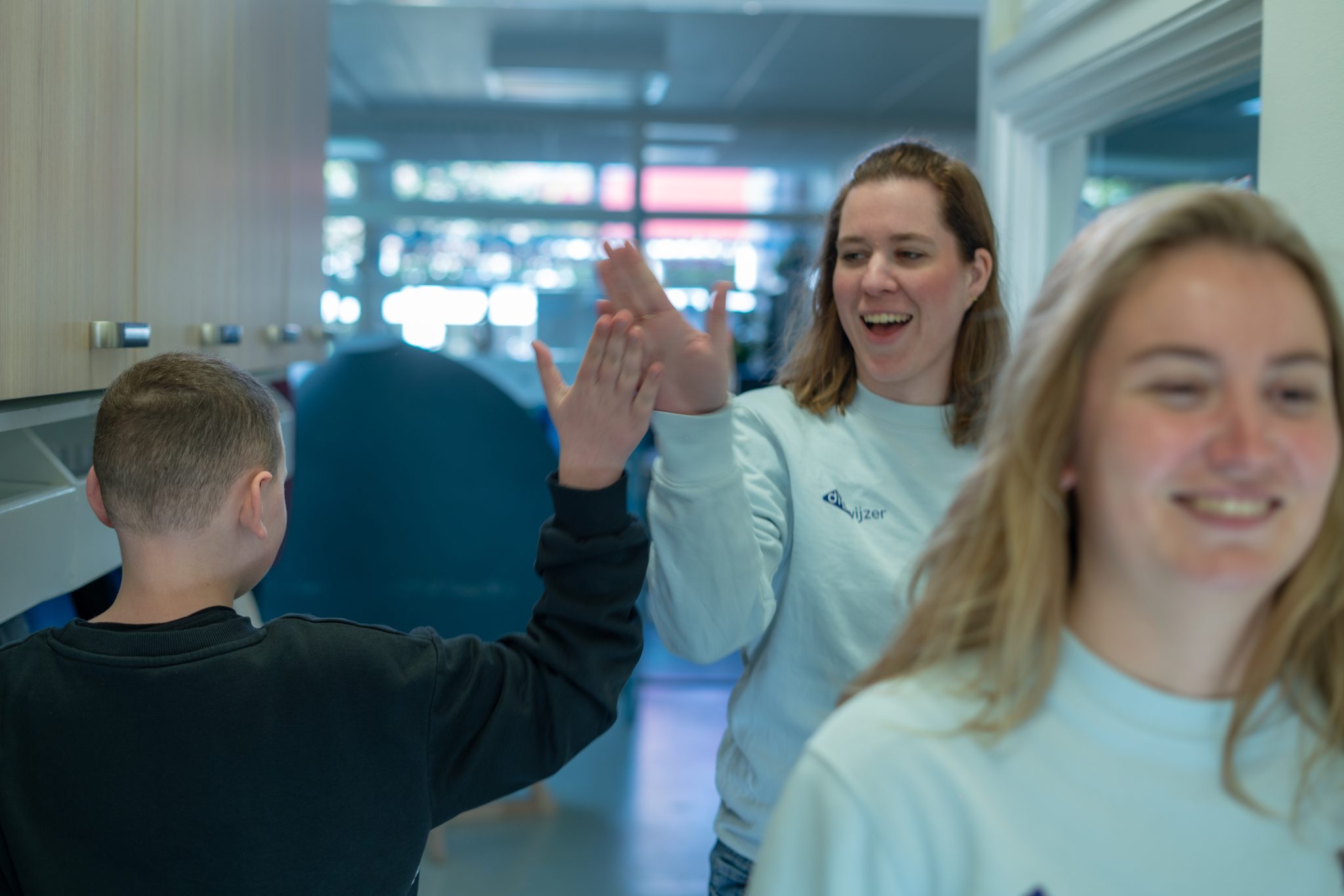 Digicoach van Digiwijzer geeft een high five aan een leerling na een interactieve les.