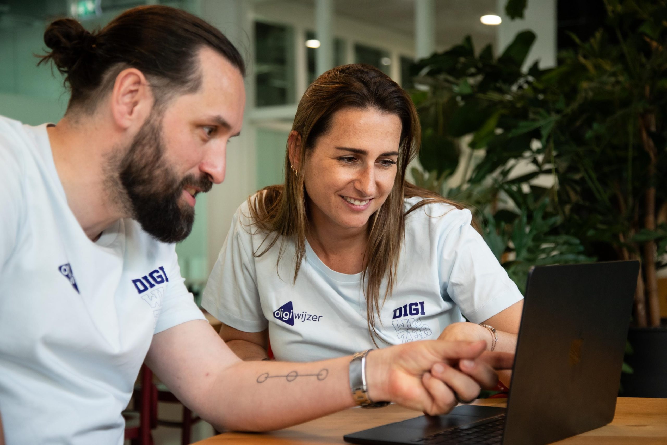 Twee Digiwijzer Digicoaches werken samen achter een laptop tijdens een overleg over digitale geletterdheid.