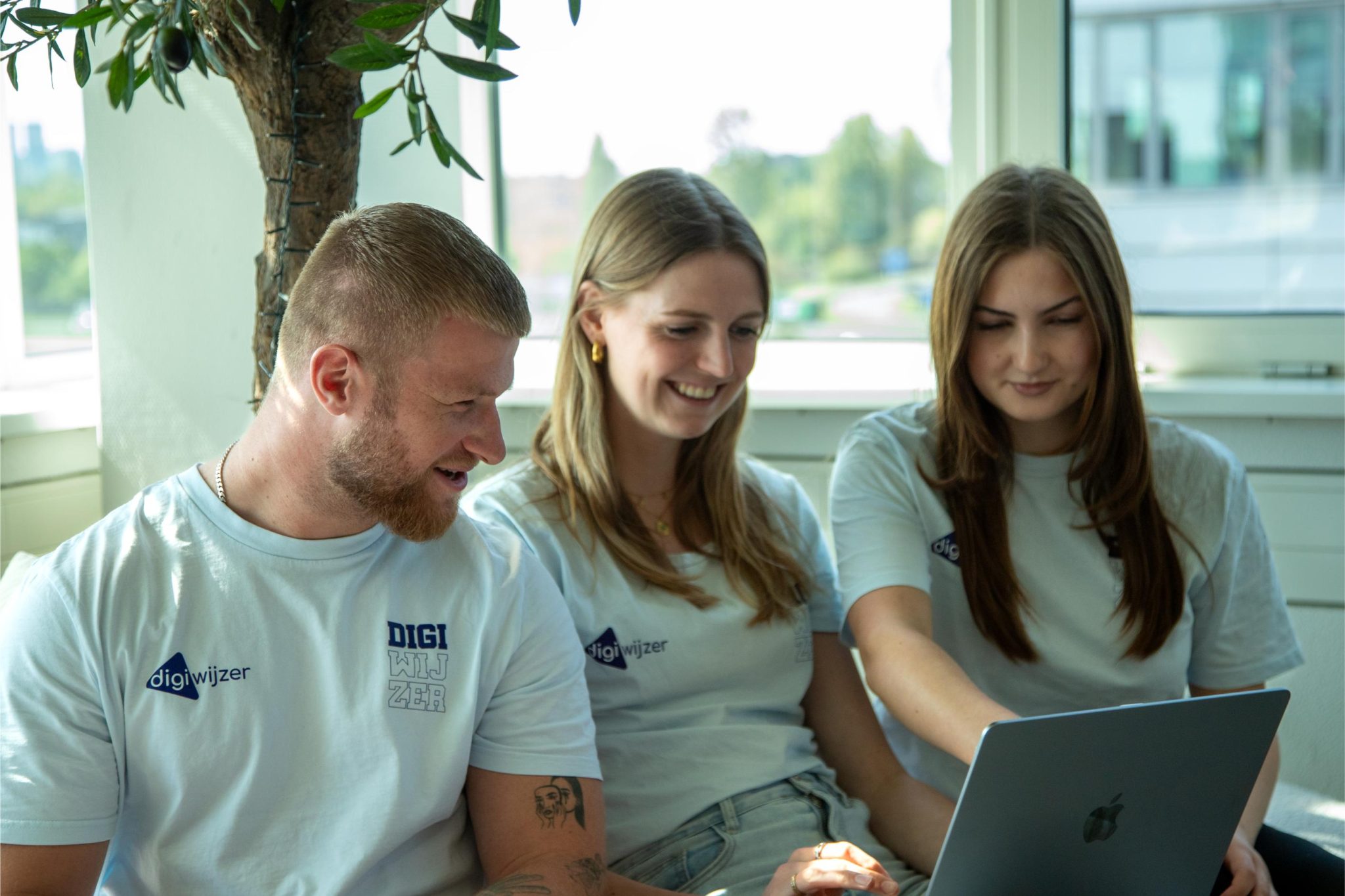 Teamleden van Digiwijzer werken samen achter een laptop tijdens een creatieve brainstormsessie.