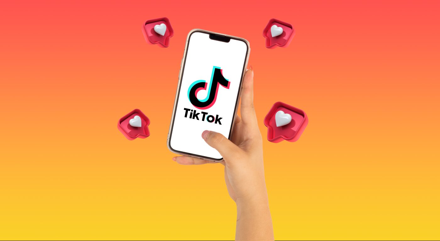 Hand houdt smartphone vast met TikTok-logo op scherm, omringd door like-icoontjes.
