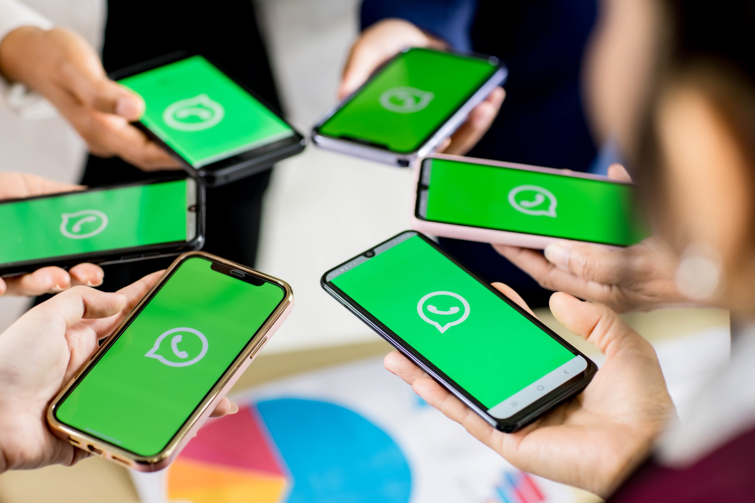 Mensen houden smartphones vast met het WhatsApp-logo op het scherm.