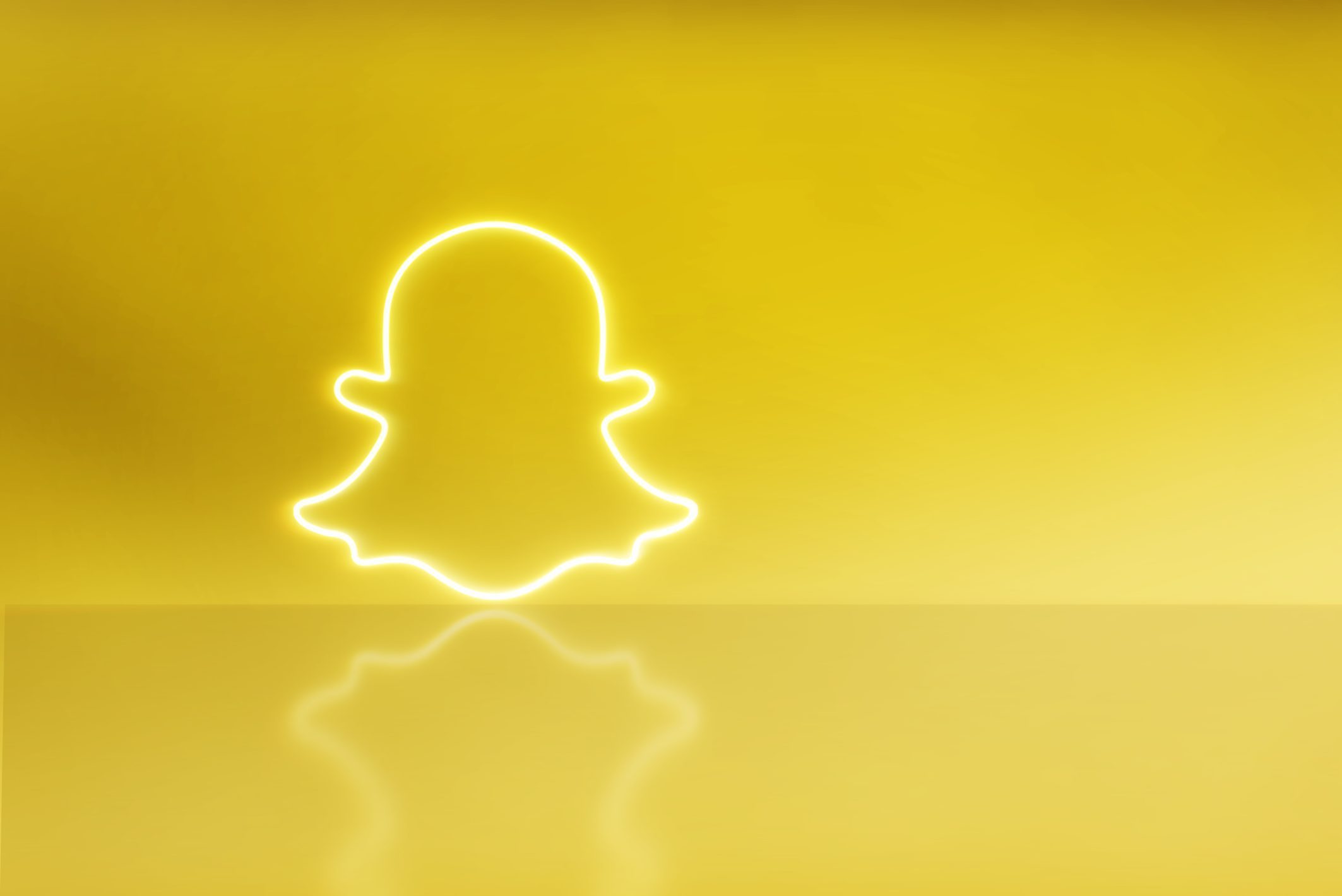 “Wit neon-omlijnd Snapchat-spooklogo op een felgele achtergrond met reflectie en veel lege ruimte rechts.”