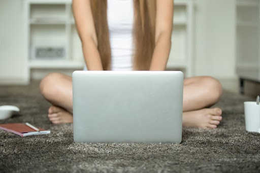 Jongere zit met een laptop op schoot terwijl ze online chat of video gebruikt