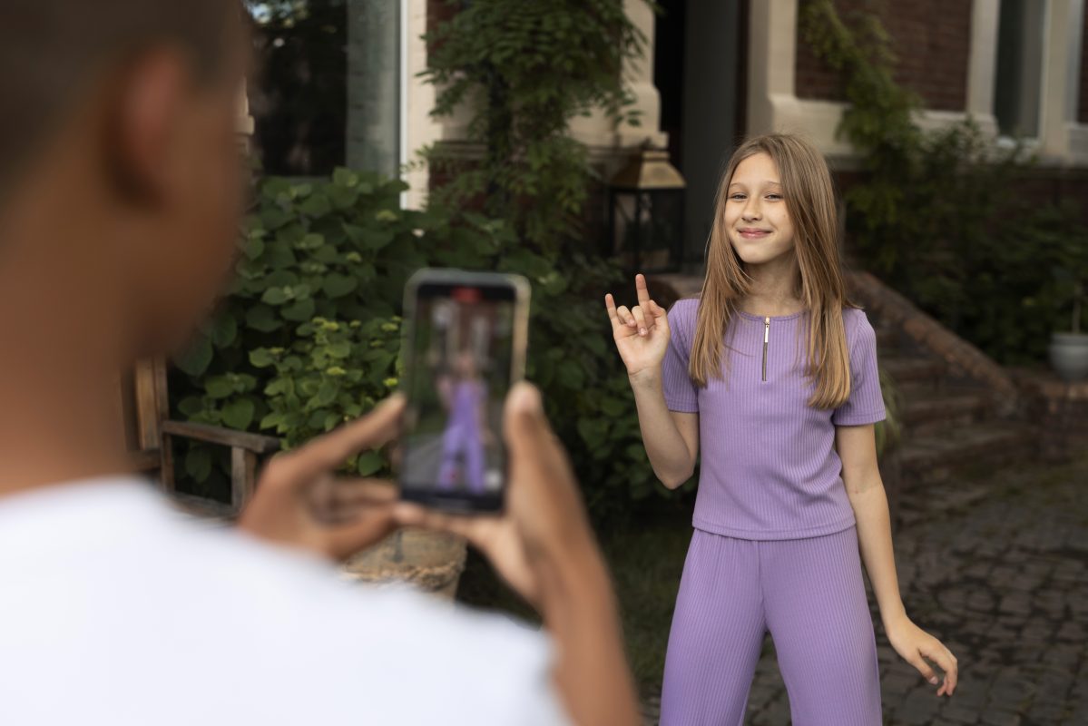 Jong meisje wordt gefilmd met een smartphone terwijl ze een TikTok-achtig video-opname maakt in een tuin