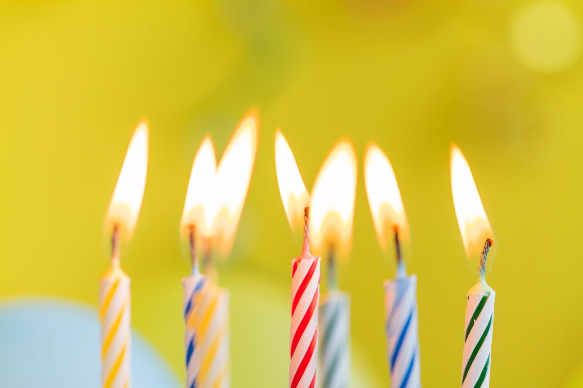 Brandende verjaardagstaartkaarsen in verschillende kleuren, als symbool voor leeftijd en ontwikkeling.