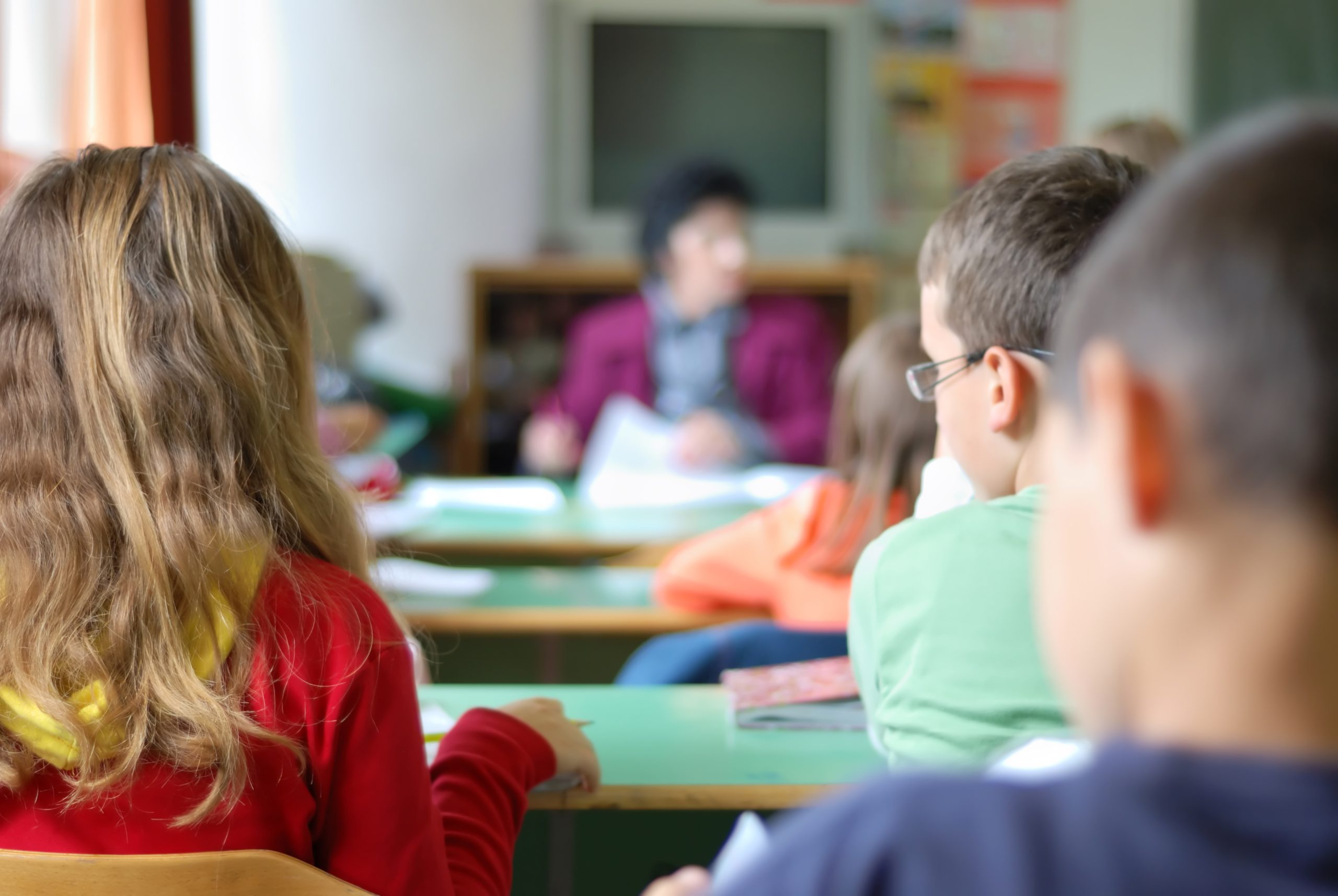 Leerlingen in een klaslokaal luisteren naar de docent tijdens een les over burgerschap en digitale vaardigheden