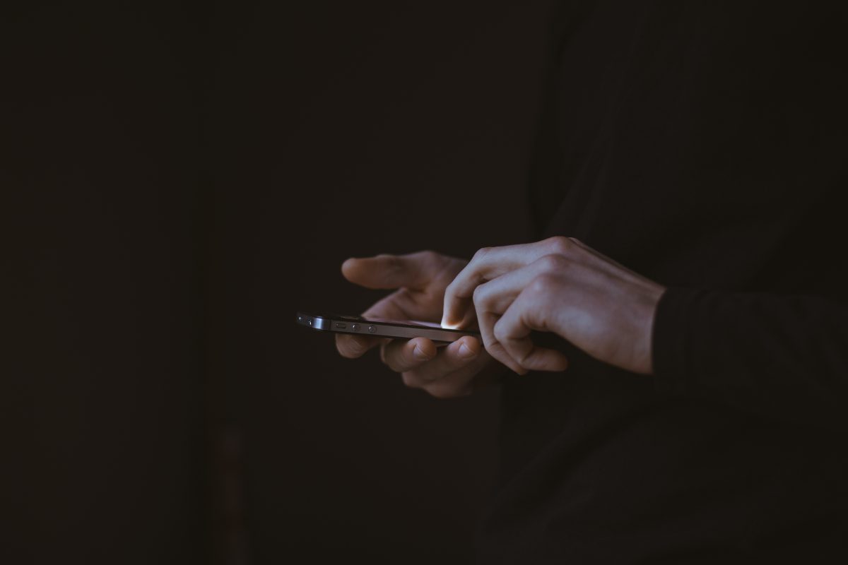 Jongere gebruikt smartphone in het donker, symbool voor online contact en risico op benadering door ronselaars