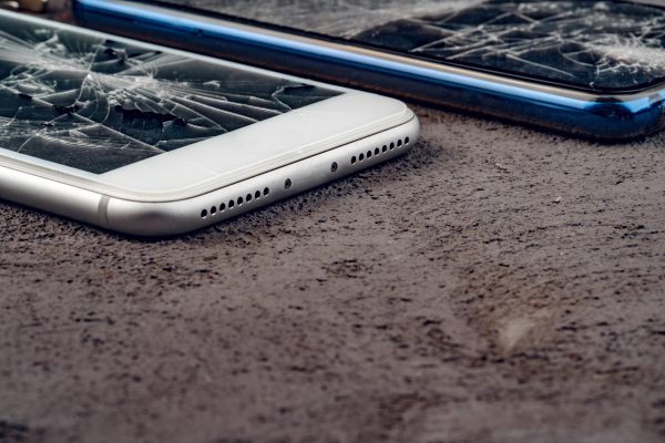 Kapotte smartphones op straat die symbool staan voor het vastleggen en delen van schokkende beelden door jongeren