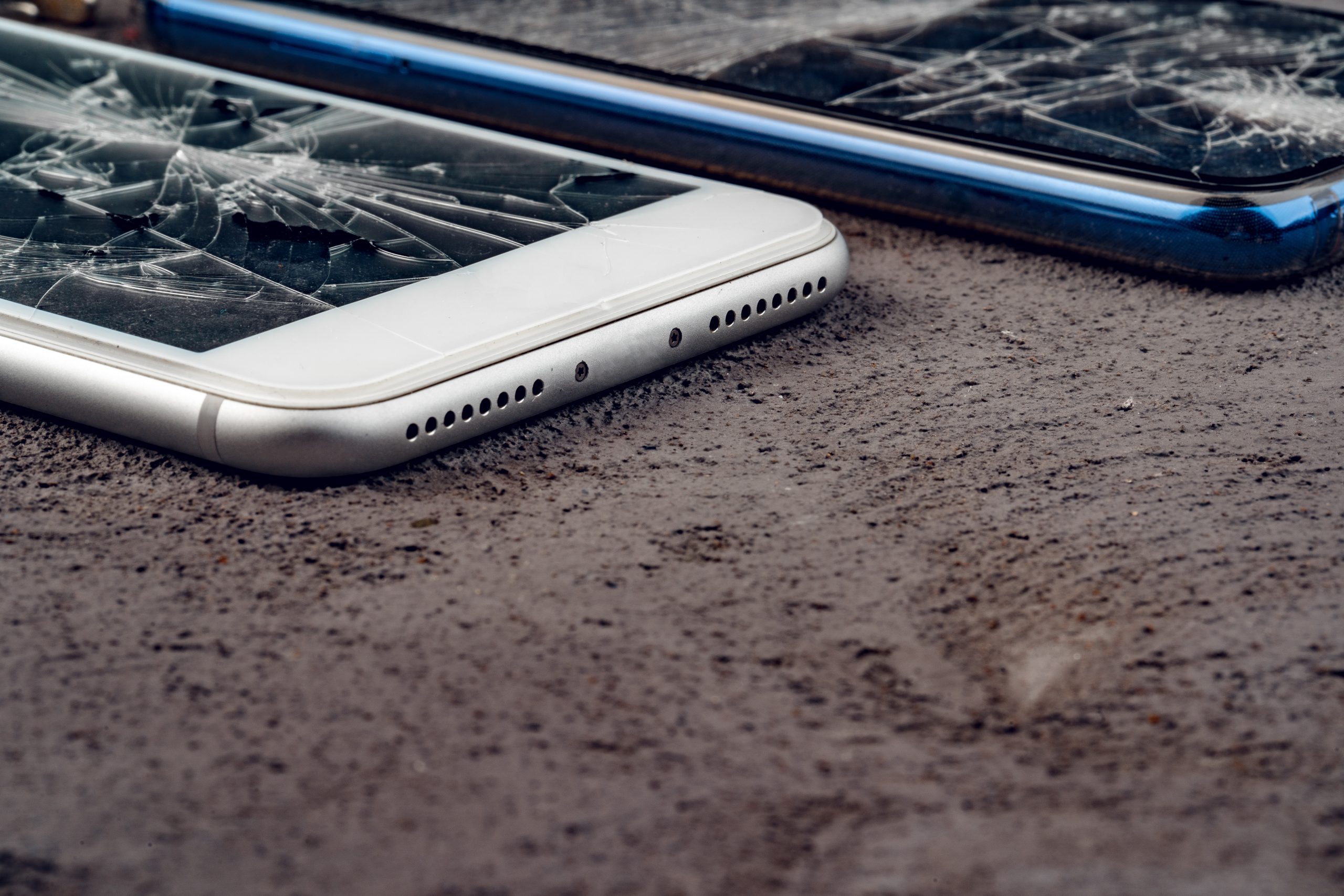 Kapotte smartphones op straat die symbool staan voor het vastleggen en delen van schokkende beelden door jongeren