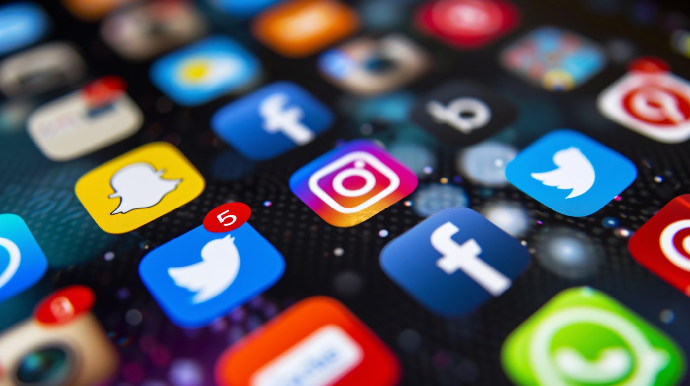 Social media-apps zoals Instagram, Snapchat, Facebook en WhatsApp weergegeven op een smartphonescherm als symbool voor schermtijd en online communicatie onder jongeren.
