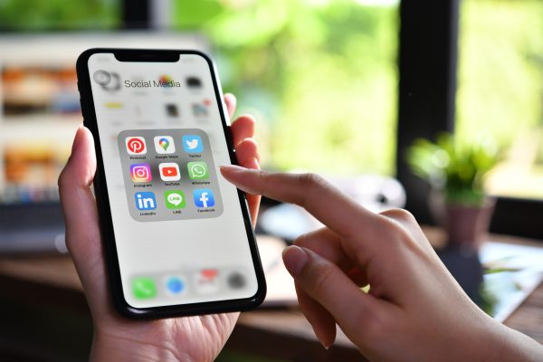 Jongere gebruikt smartphone met social media apps zoals Instagram, TikTok en WhatsApp op het scherm