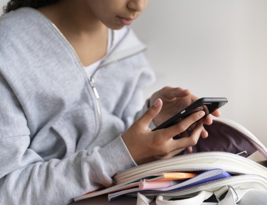 Kind gebruikt smartphone met schooltas, voorbeeld van digitale vaardigheden kinderen en online gedrag