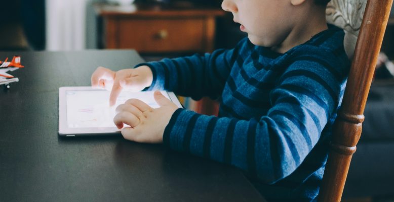jong kind gebruikt tablet aan tafel meerdere digitale apparaten jonge kinderen
