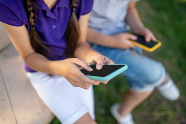 Twee jongeren zitten buiten met een smartphone in hun hand, een beeld dat past bij het thema digitale dementie en de invloed van technologie op geheugen en concentratie.
