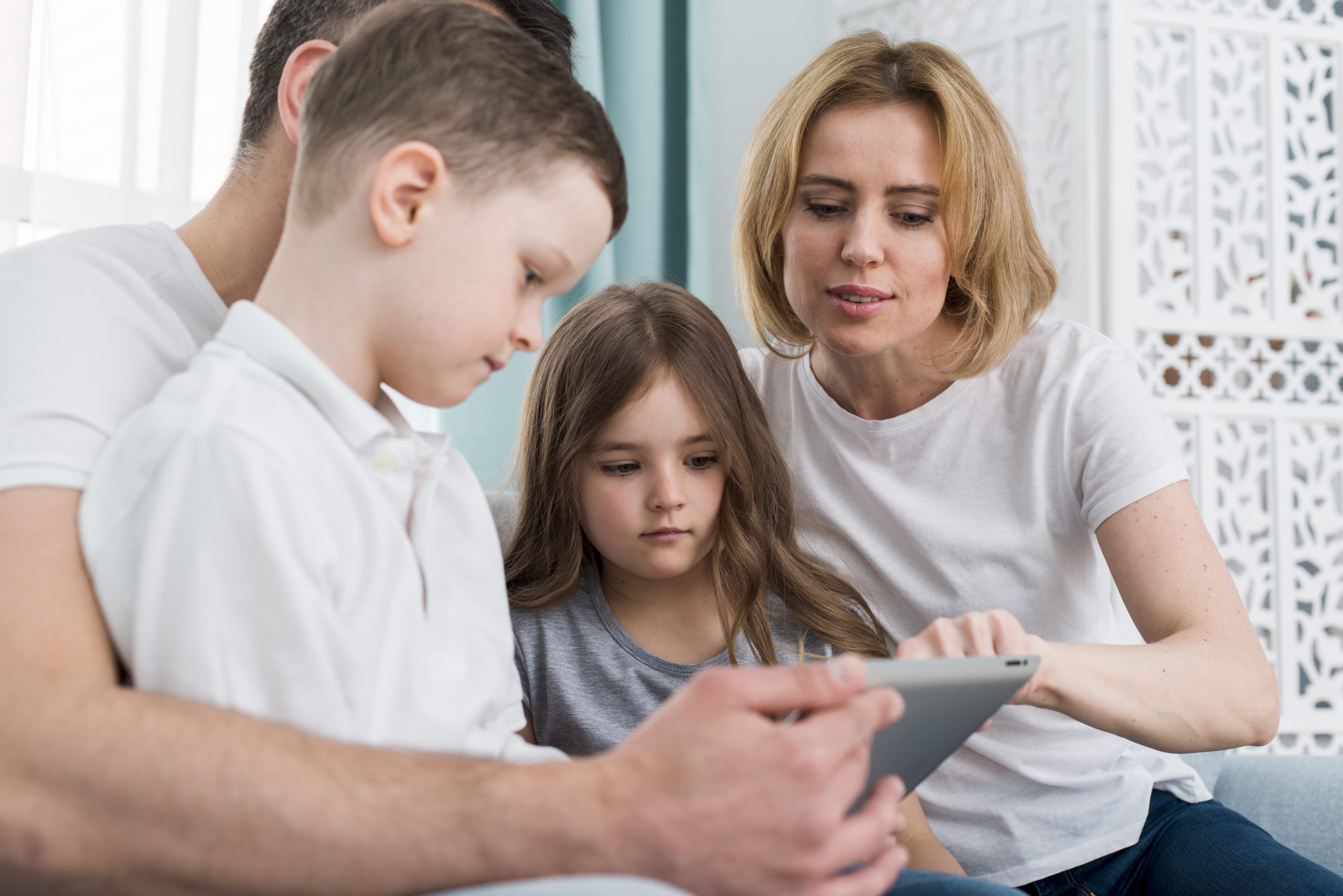 Ouders begeleiden hun kinderen bij het gebruik van een tablet thuis en bespreken samen digitale instellingen en online veiligheid.