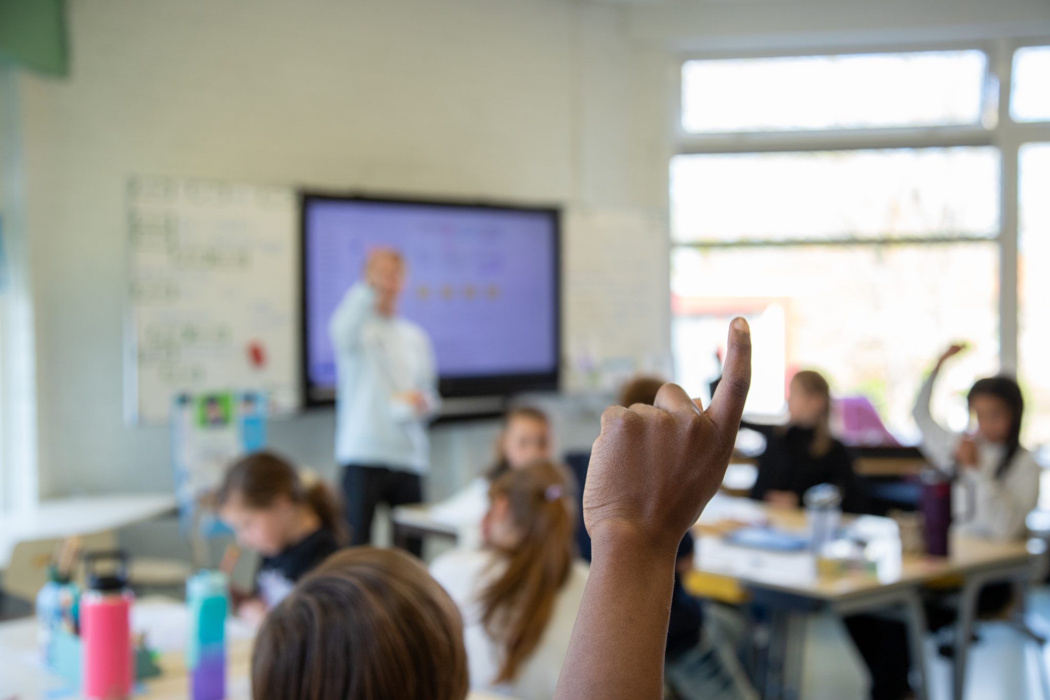 Leerling steekt zijn hand op tijdens een les over digitale weerbaarheid in de klas.