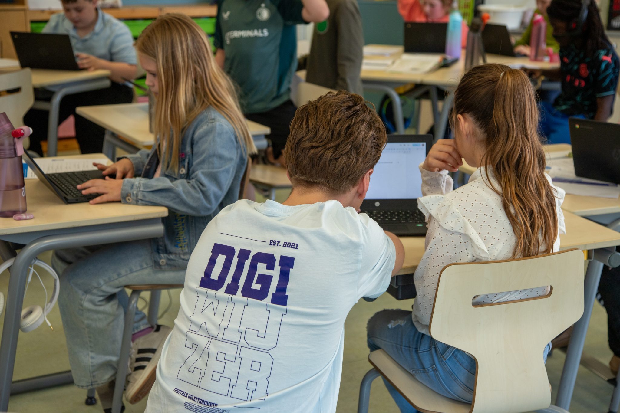 Een vakleerkracht van Digiwijzer begeleidt leerlingen tijdens een les digitale geletterdheid op de basisschool.
