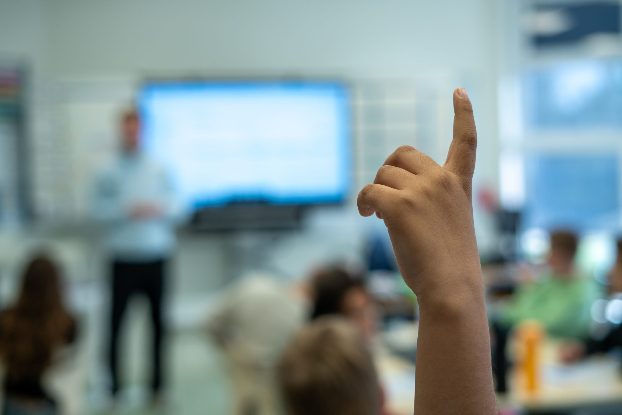 Leerling steekt een vinger op tijdens een les digitale geletterdheid in de klas.