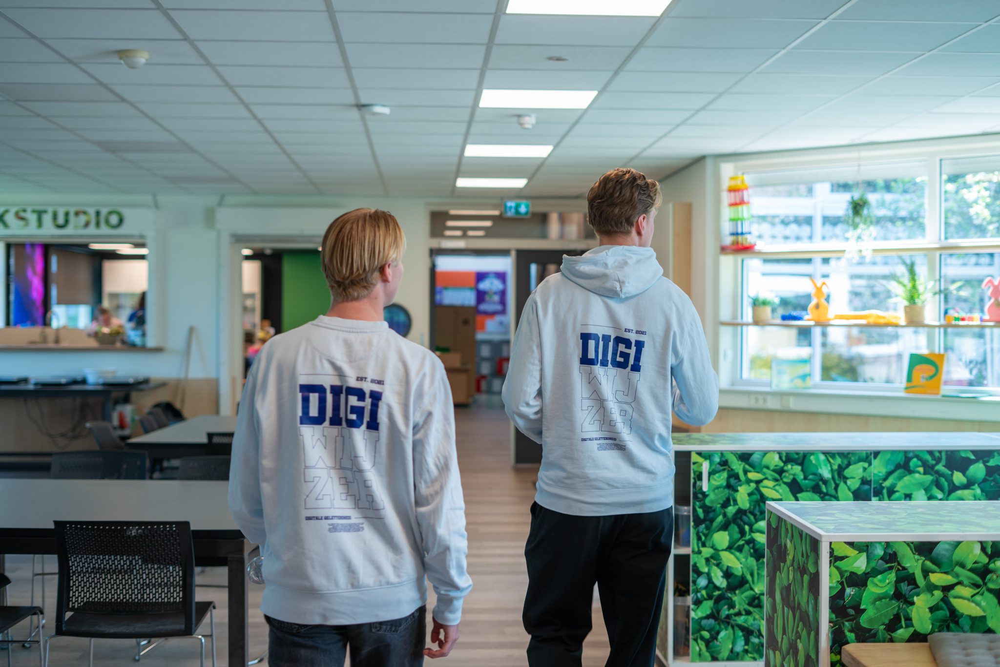 Twee vakleerkrachten van Digiwijzer lopen door een basisschool op weg naar een les digitale geletterdheid.