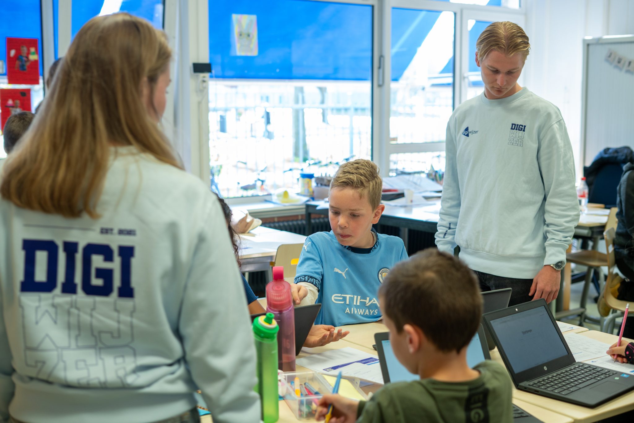Digiwijzer-digicoaches begeleiden leerlingen tijdens een les digitale geletterdheid in de klas.