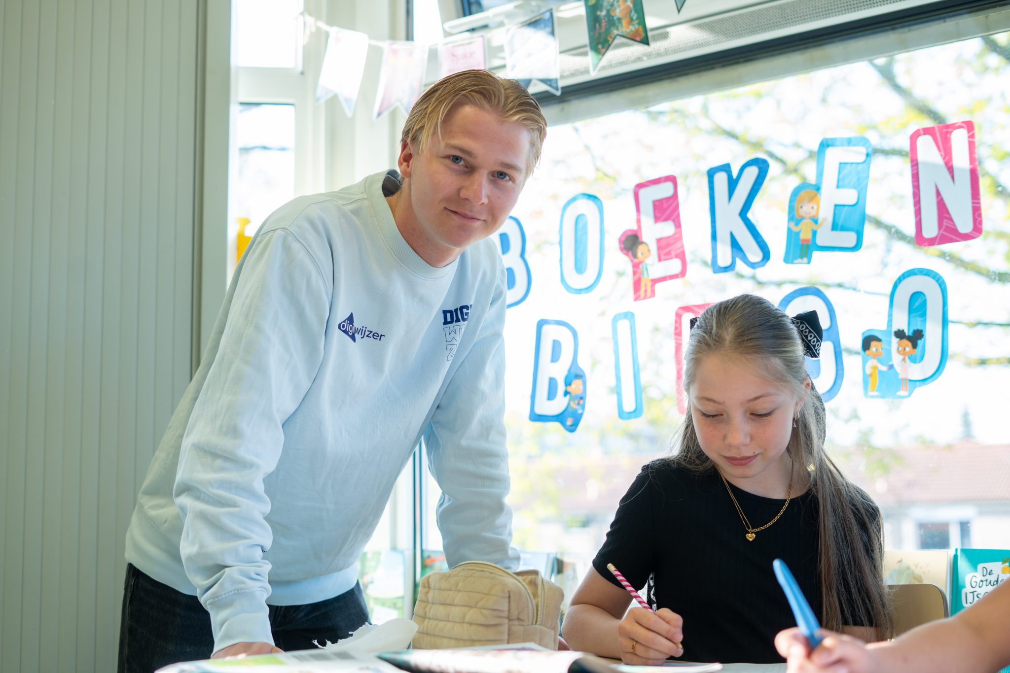 Digicoach begeleidt een leerling tijdens een les digitale geletterdheid in de klas.