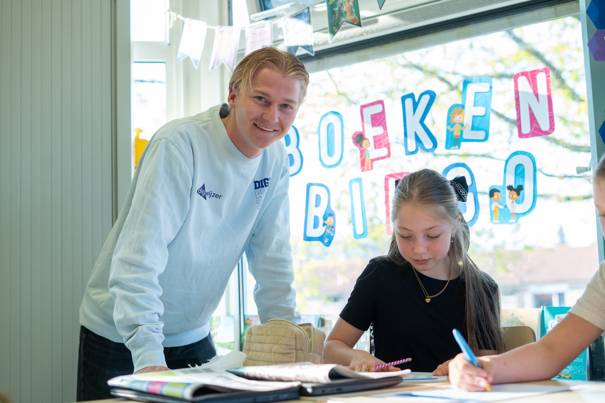 Een Digiwijzer-vakleerkracht begeleidt een leerling tijdens een les digitale geletterdheid in het speciaal basisonderwijs.