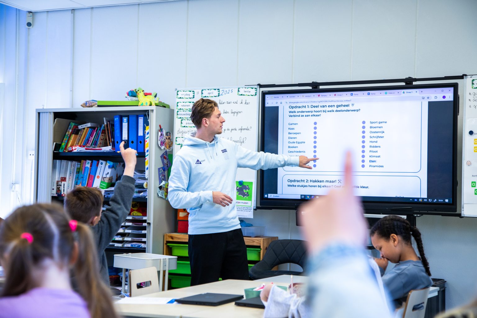 Digicoach van Digiwijzer geeft een interactieve les aan leerlingen met een digitaal lesbord over digitale geletterdheid.