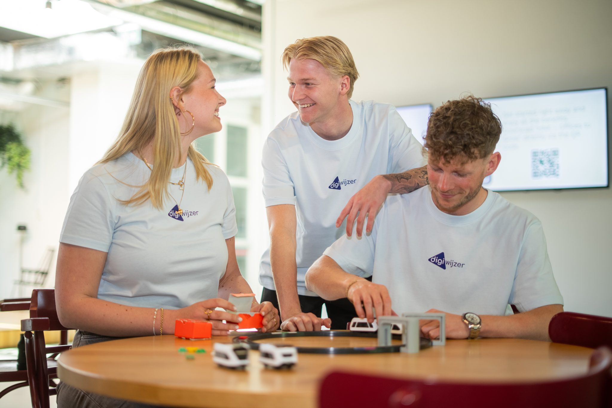 Drie medewerkers van Digiwijzer overleggen tijdens het testen van educatief lesmateriaal.