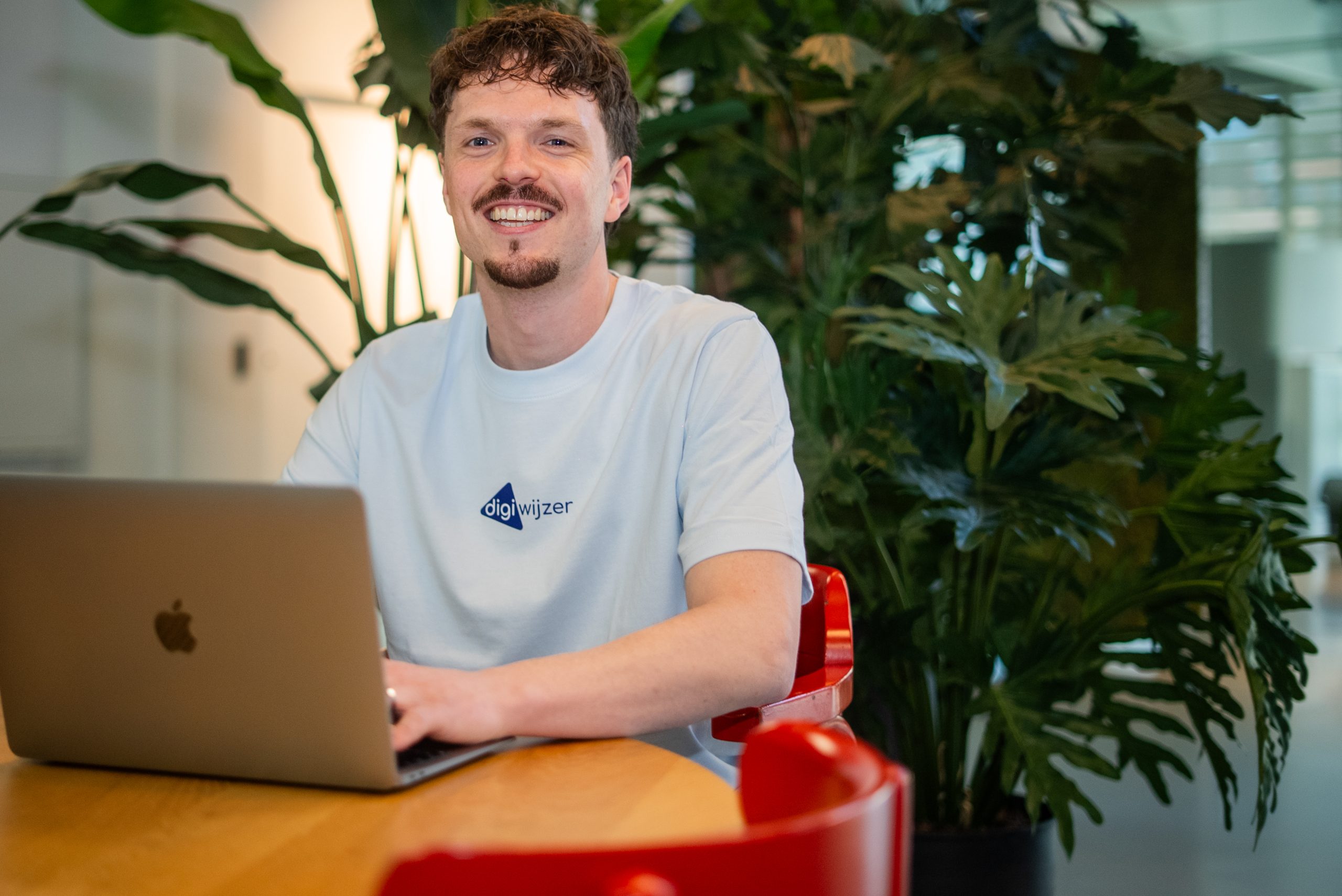 Medewerker van Digiwijzer bereidt een ouderavond over digitale geletterdheid voor achter een laptop.