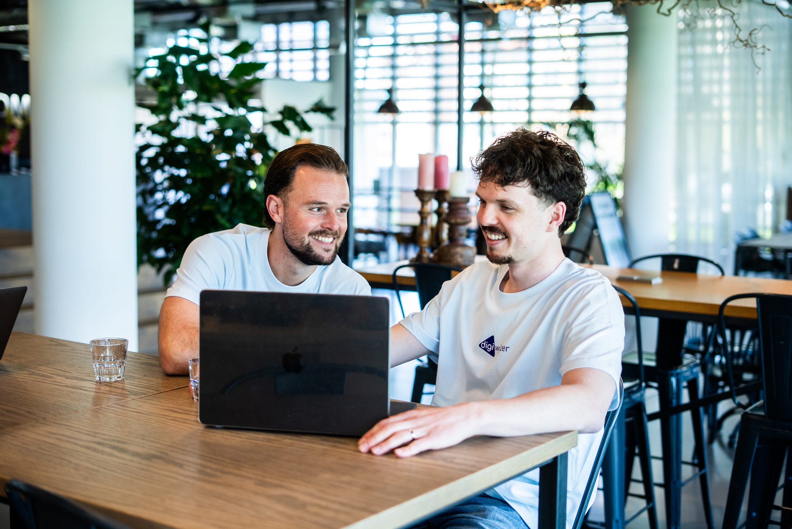 Twee medewerkers van Digiwijzer bespreken de digitale leeromgeving en lesinhoud achter een laptop.