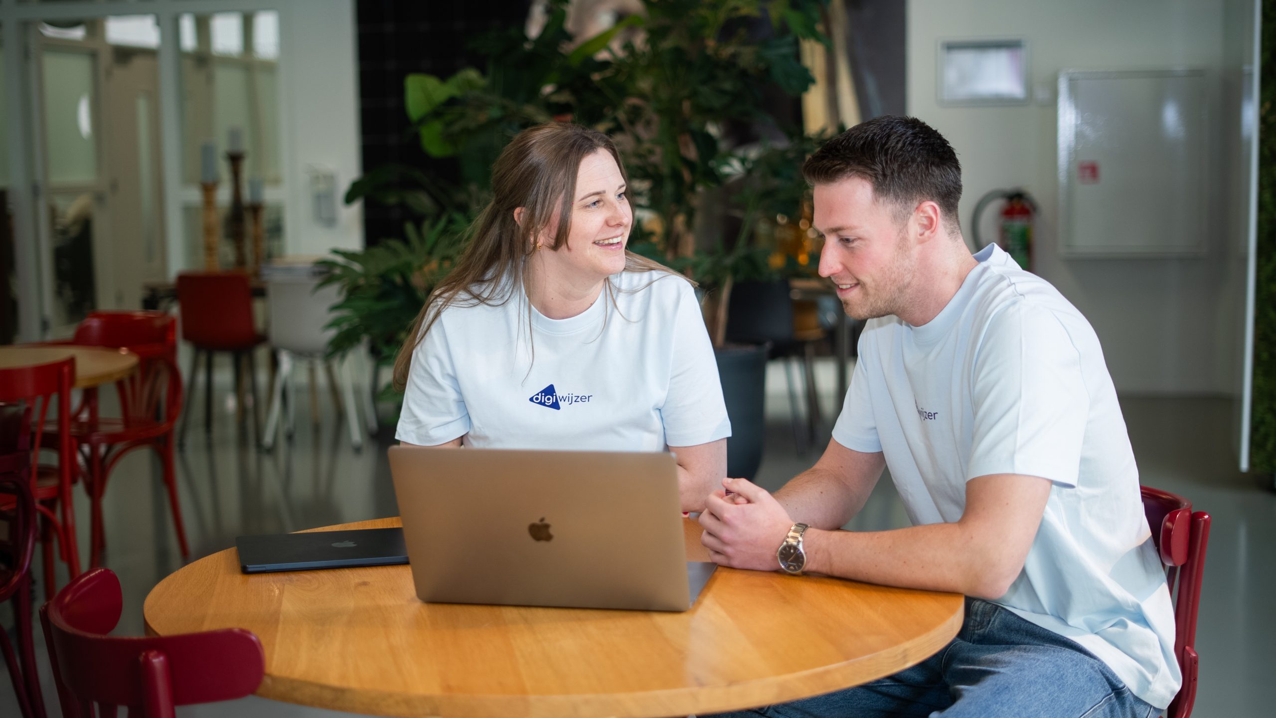 Twee Digiwijzer-medewerkers bespreken een social media protocol op een laptop.