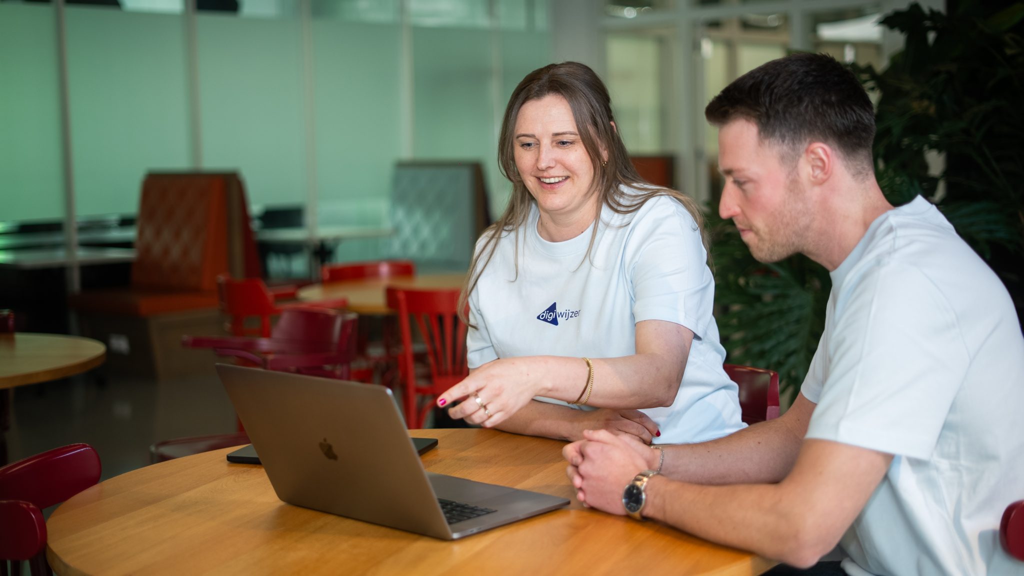 Twee Digiwijzer-specialisten bespreken digitale veiligheid en advies aan een laptop.
