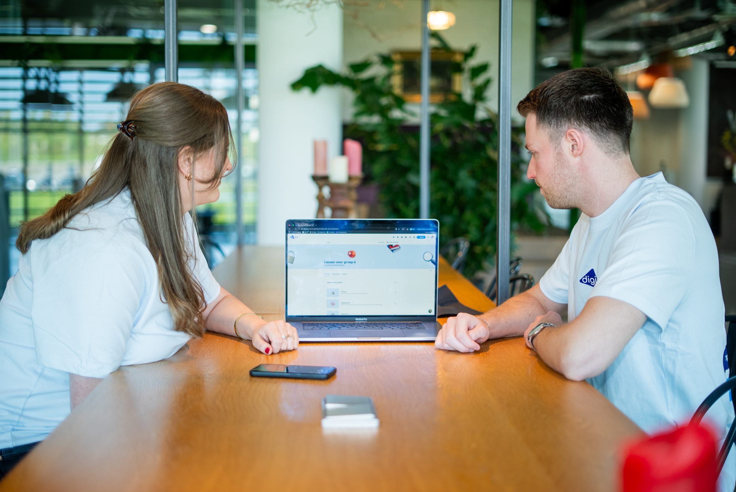 Twee medewerkers van Digiwijzer bekijken samen digitaal lesmateriaal over burgerschap op een laptop.