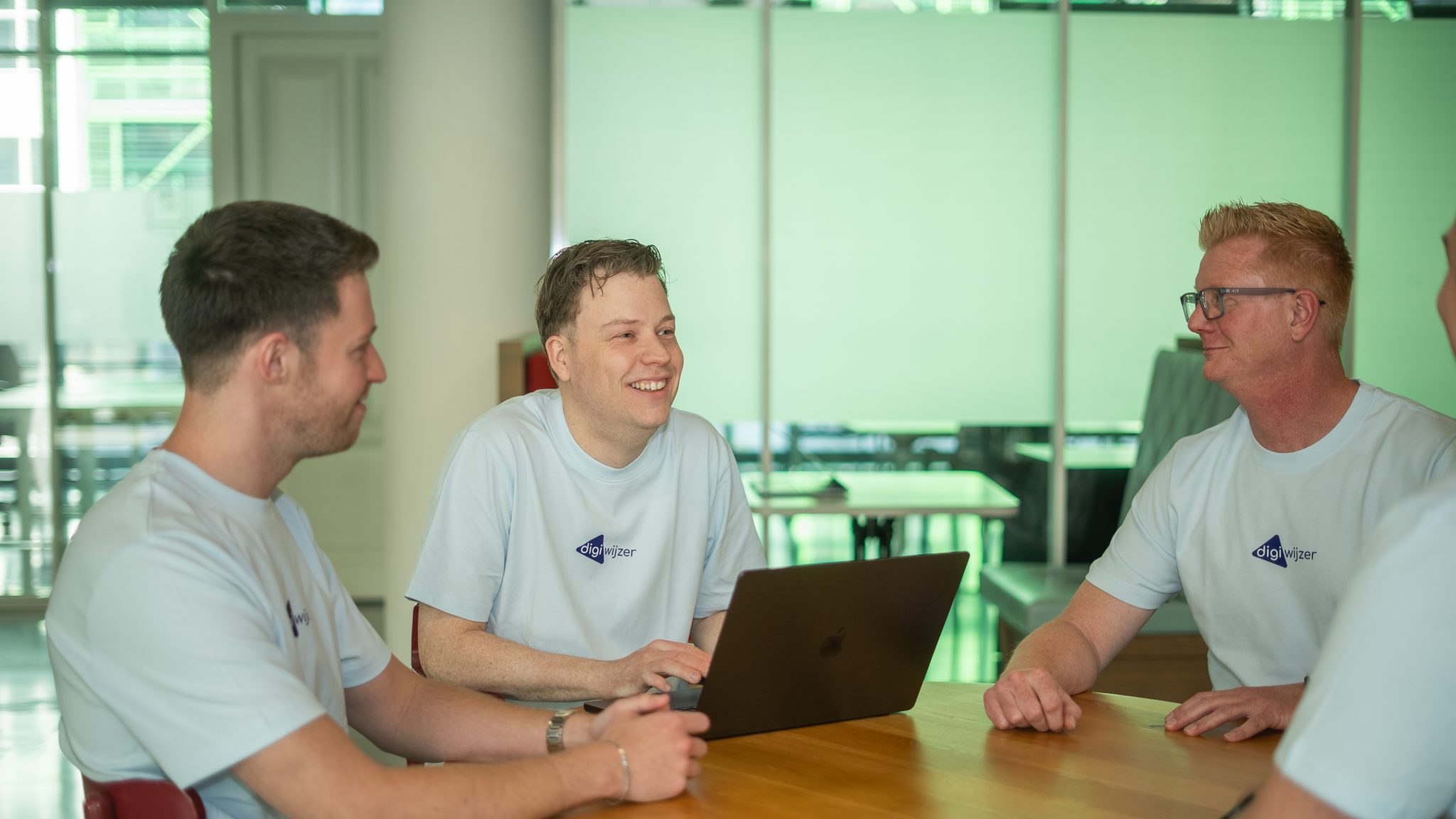 Drie medewerkers van Digiwijzer bespreken samen met een laptop de voorbereiding van co-teaching lessen digitale geletterdheid.