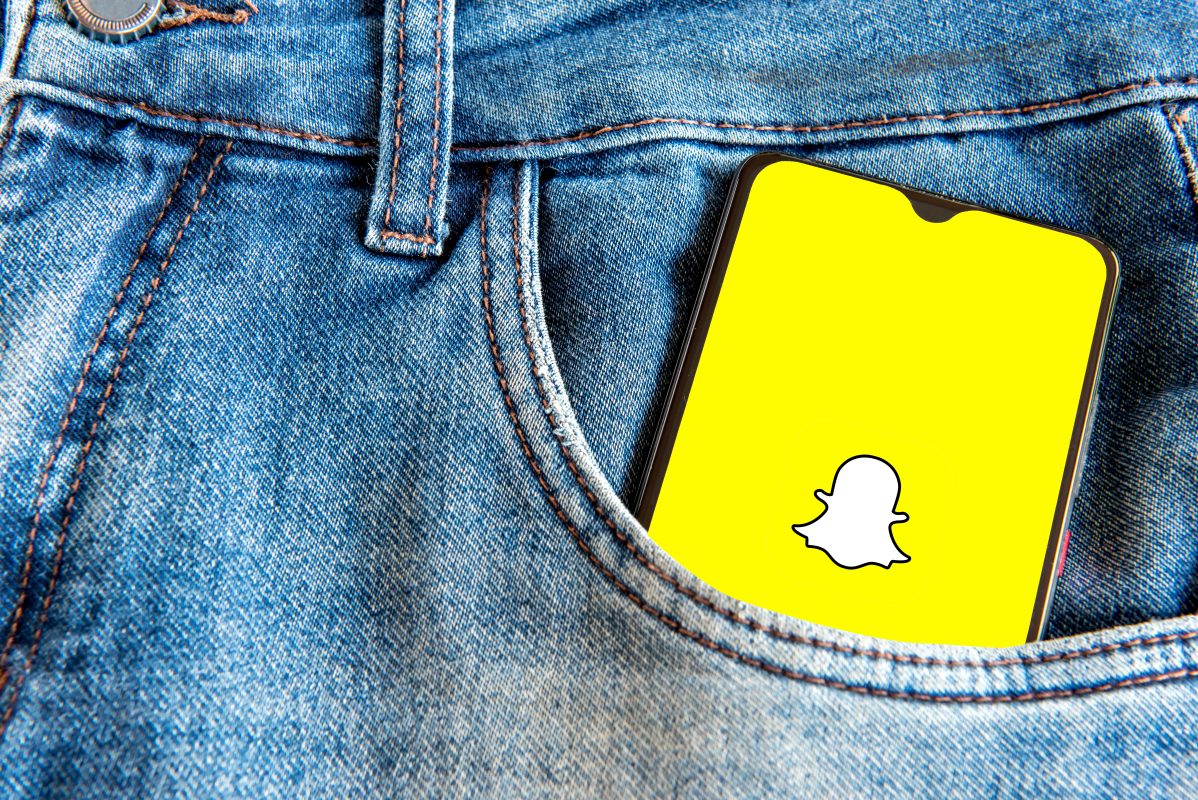 Smartphone met Snapchat-logo in een spijkerbroekzak, passend bij Snapchat advertenties in chats.