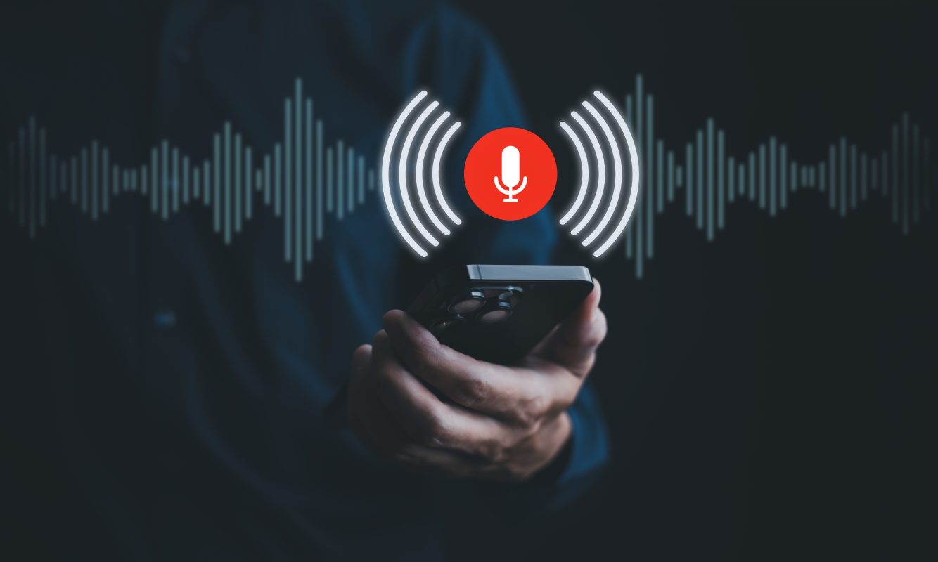 Persoon met smartphone en geluidsgolven als illustratie van voice cloning met AI.