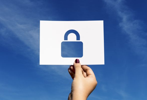 Hand houdt een kaart met een open hangslot vast tegen een blauwe achtergrond, als symbool voor online privacy en een privéaccount op social media.