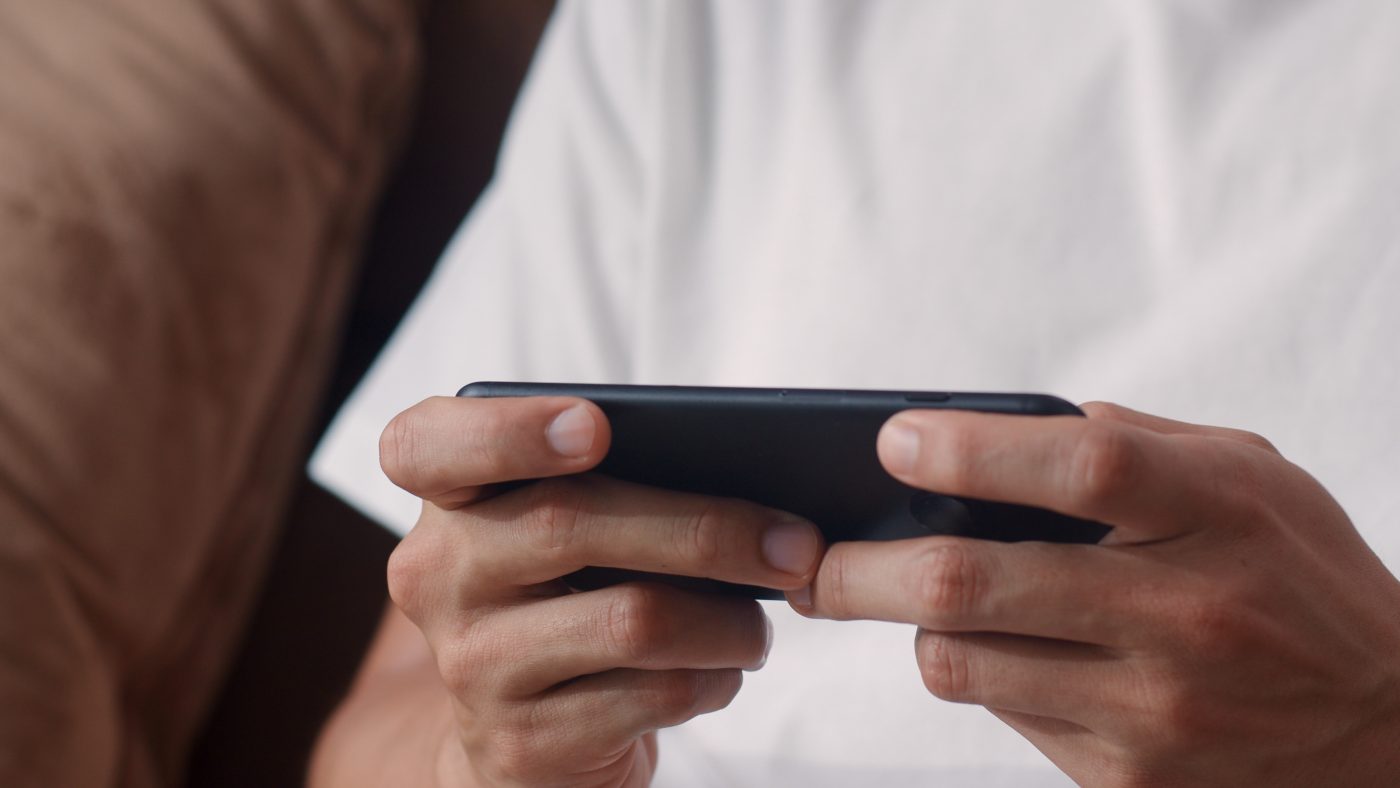 Persoon speelt een game op een smartphone, passend bij TikTok-video’s over geld verdienen met games.