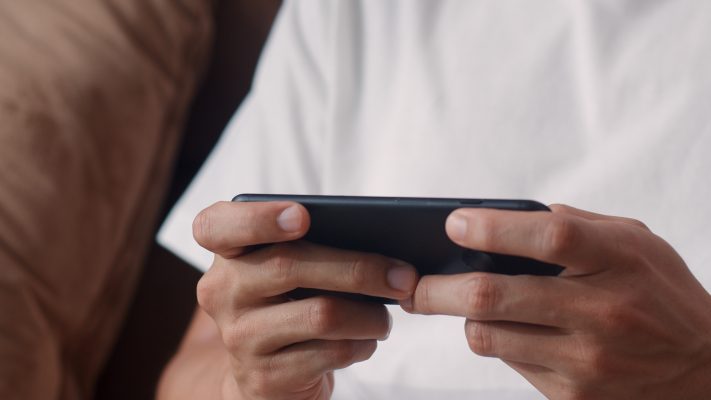 Persoon speelt een game op een smartphone, passend bij TikTok-video’s over geld verdienen met games.