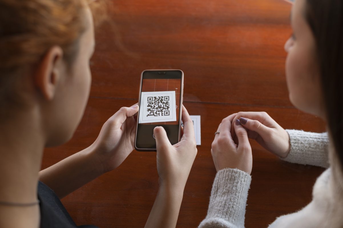 Twee personen scannen een QR-code met een smartphone om digitale informatie te openen.