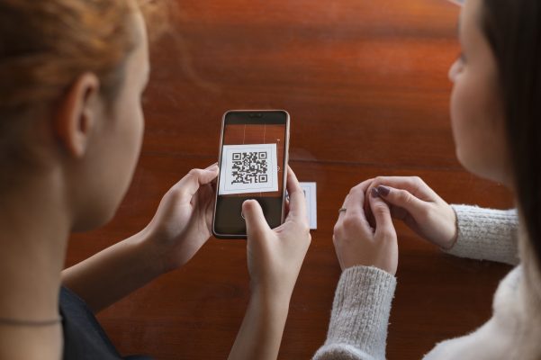 Twee personen scannen een QR-code met een smartphone om digitale informatie te openen.