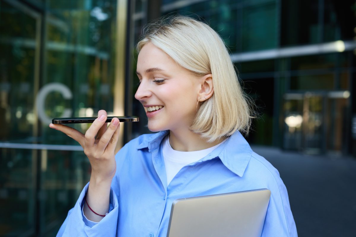 Jonge vrouw spreekt een voicebericht in op haar smartphone